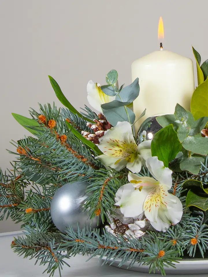 Centrotavola di fiori bianchi elementi natalizi e candela bianca dettagli